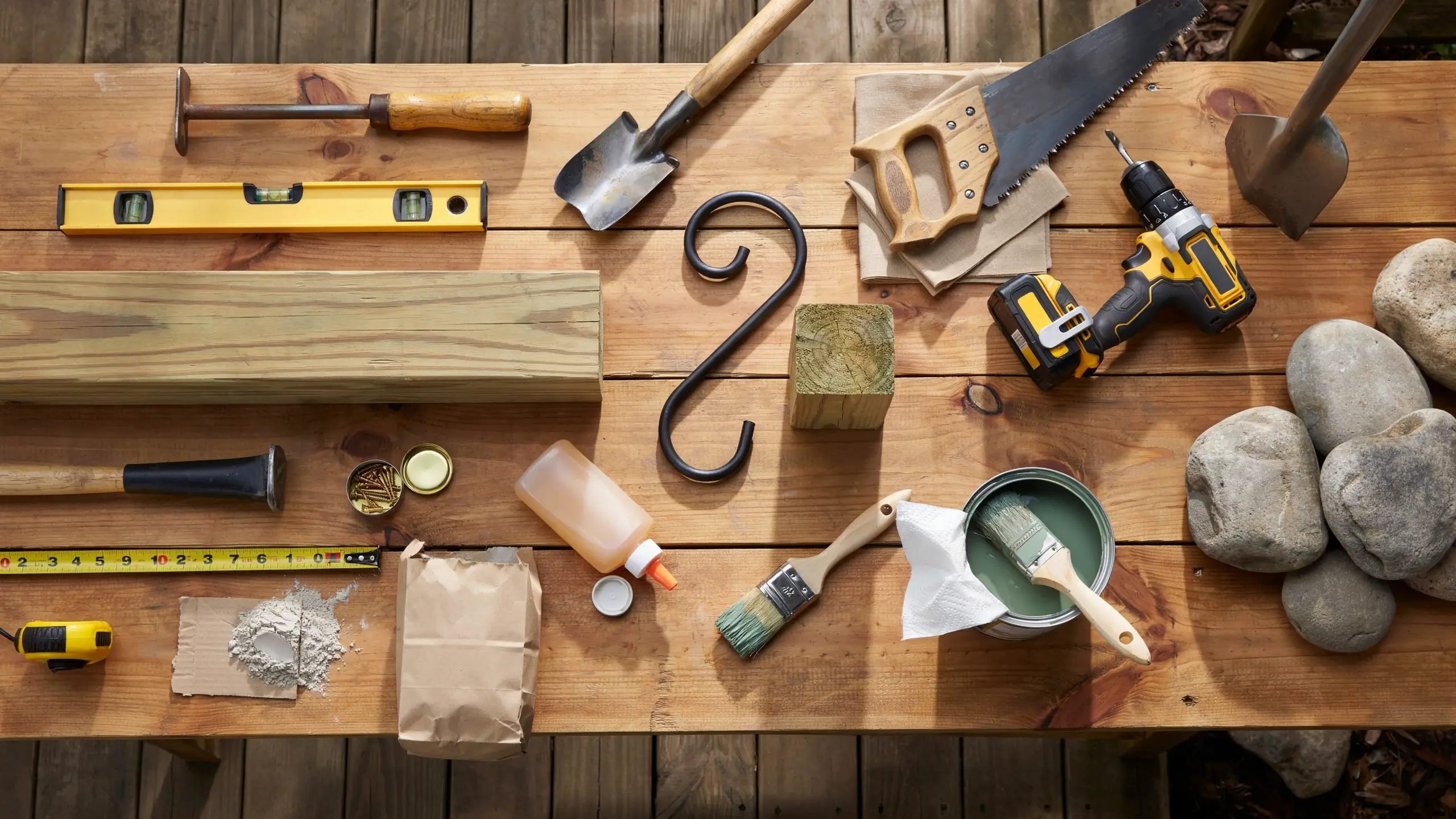 Overhead flat lay of a wood post after being cut to size and sanded smooth, surrounded by sawdust and woodworking tools on a workshop table.
