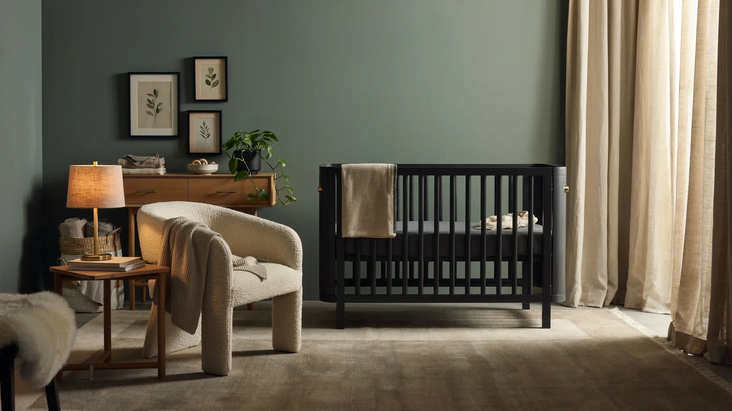 Renter-friendly nursery with sage green peel-and-stick wallpaper, black crib, cozy chair, and modern wood dresser.