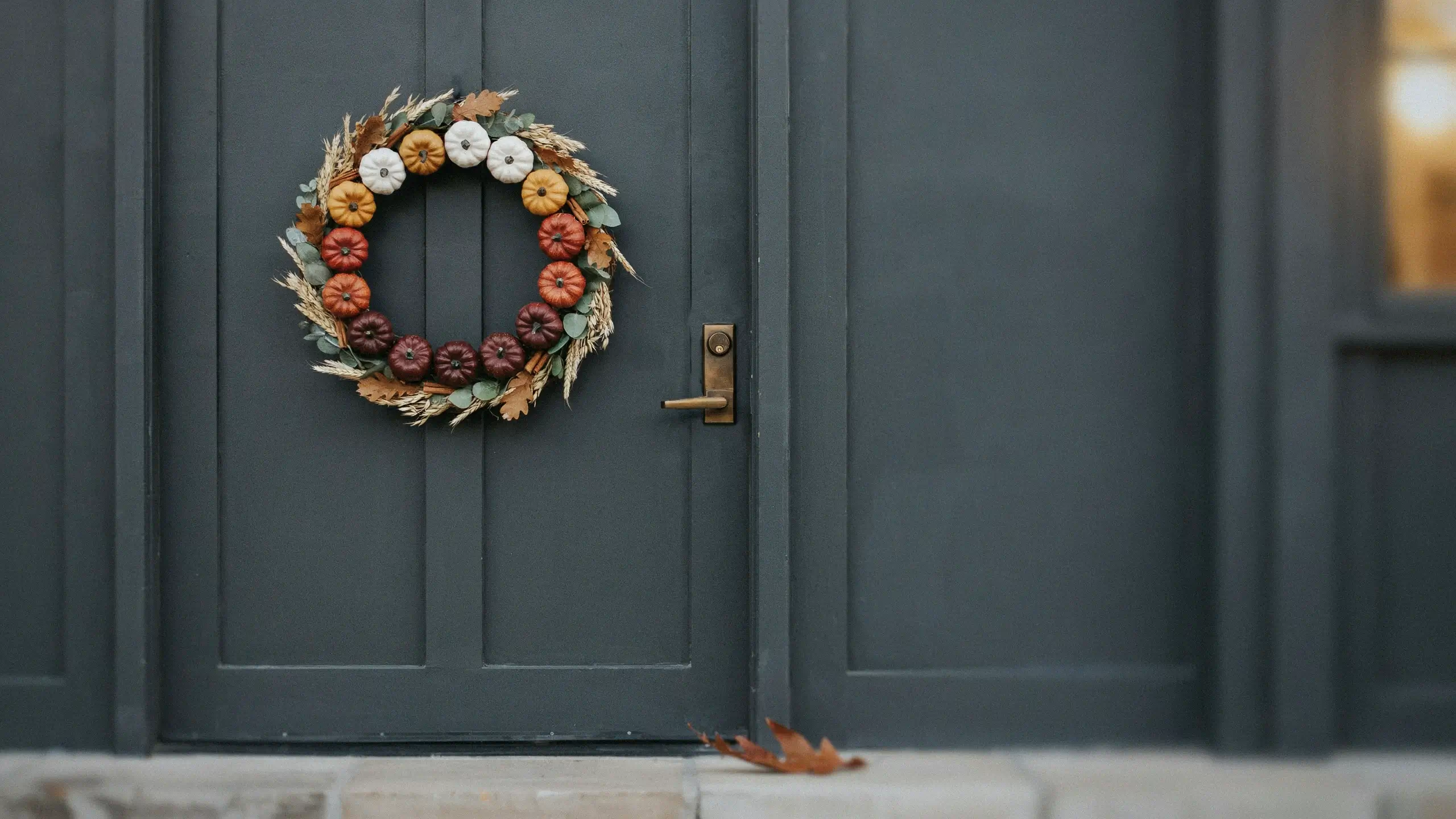 Pumpkin Spice Color-Block Wreath on dark grey door with seasonal mini pumpkins and dried botanicals.