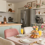 Blush pink brunch table in a girly kitchen with sage cabinets, open shelves, flowers, pastries and mimosas