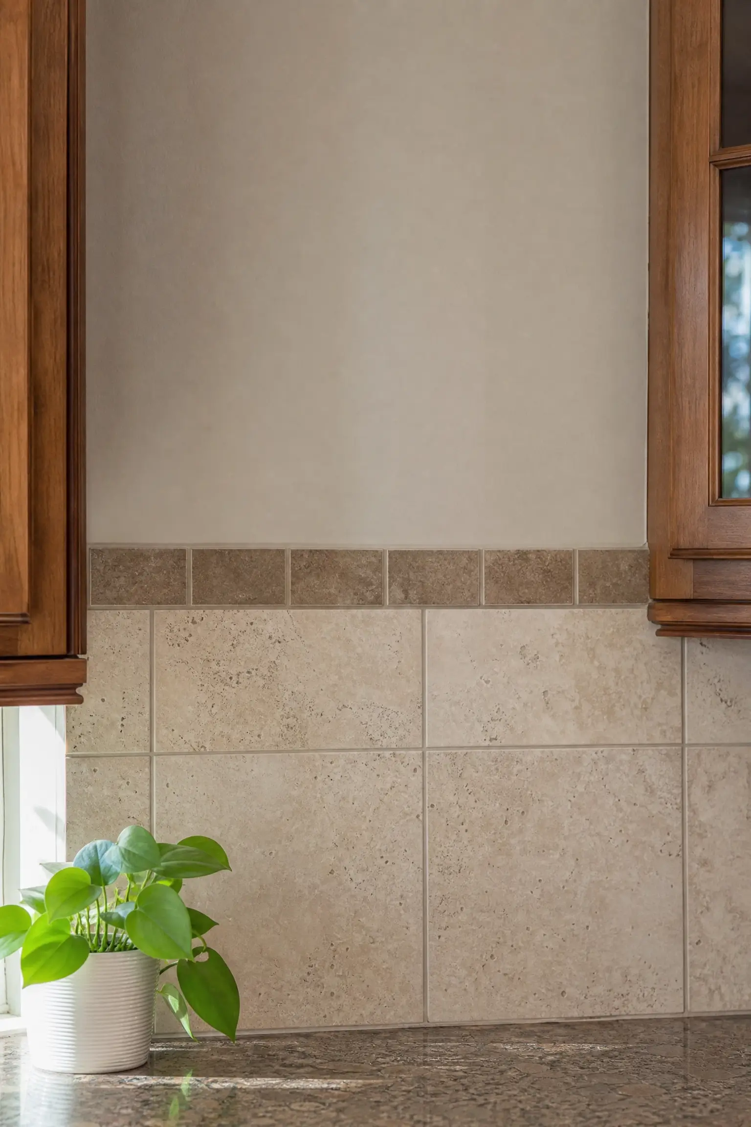 Beige kitchen backsplash with a single row of darker contrast tile bordering the painted wall above.