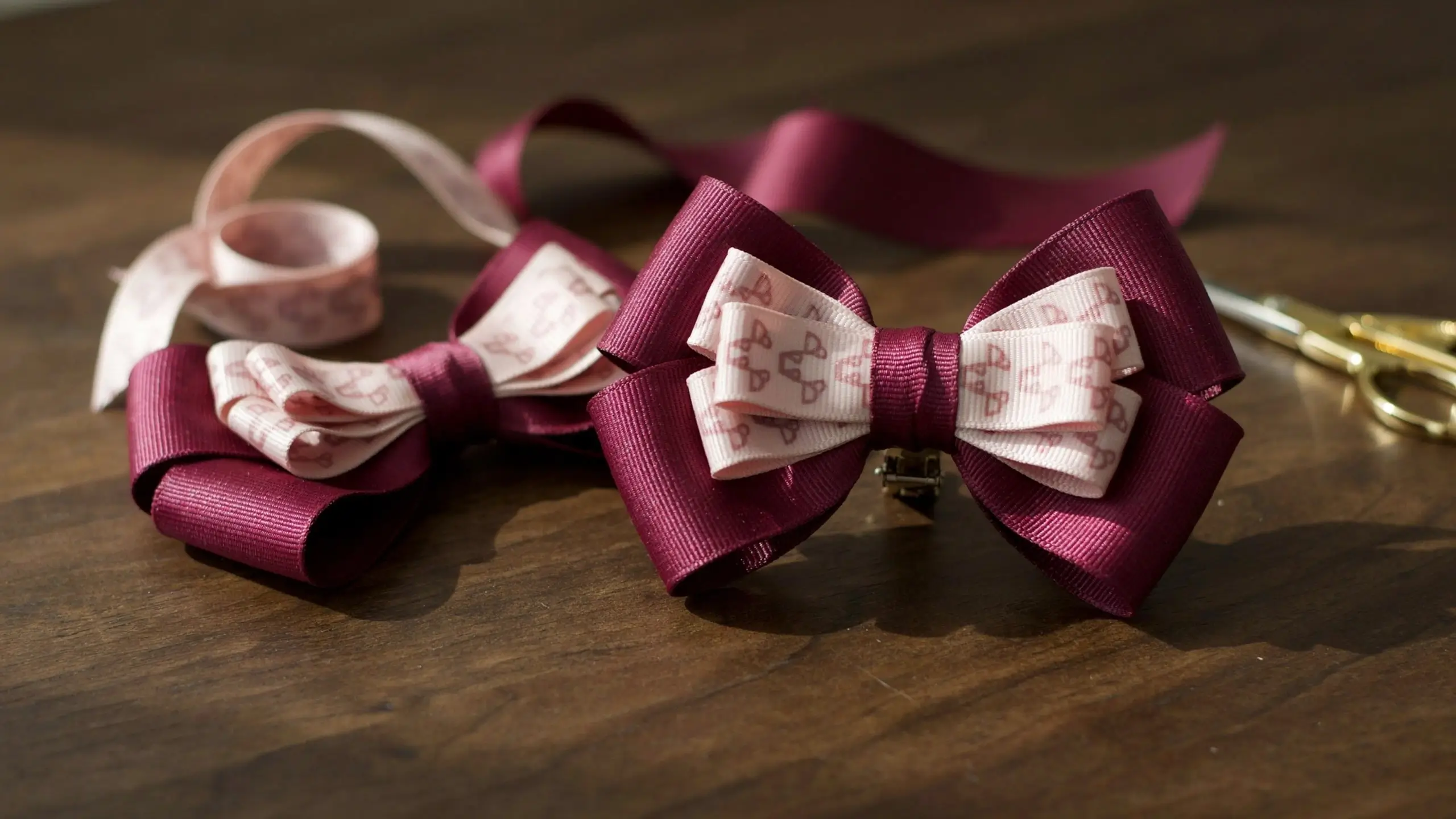 Alt Text: Burgundy and pink two-layer boutique hair bows made from grosgrain ribbon on a wooden craft table.