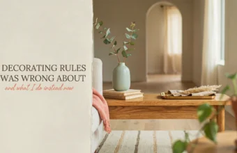 A bright, minimalist living room featuring a wooden coffee table styled with a sage green vase holding eucalyptus, a stack of books, and a wooden tray with dried grass. A white sofa with a pink throw blanket sits beside a white wall with text overlay reading '9 Decorating Rules I Was Wrong About', serving as a cover image for an interior design blog post.