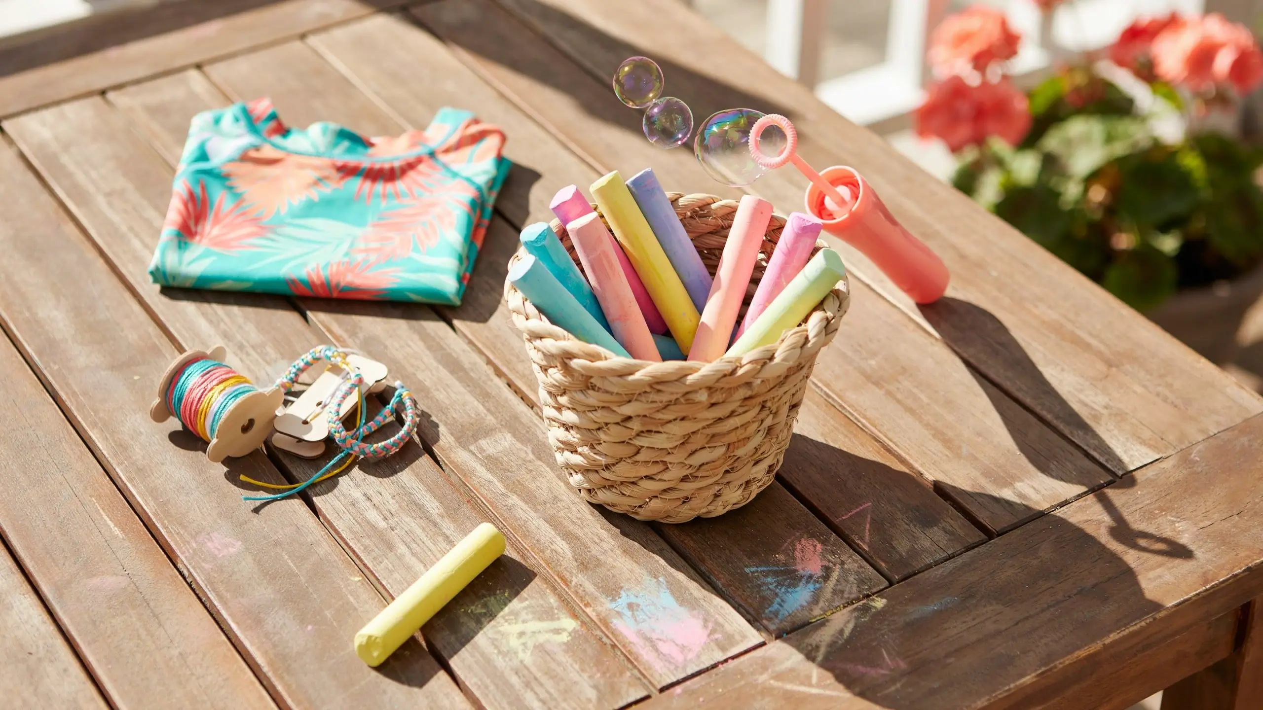 Sidewalk chalk, bubbles, and craft items on a wooden table for Easter basket ideas for kids aged 4 to 9.
