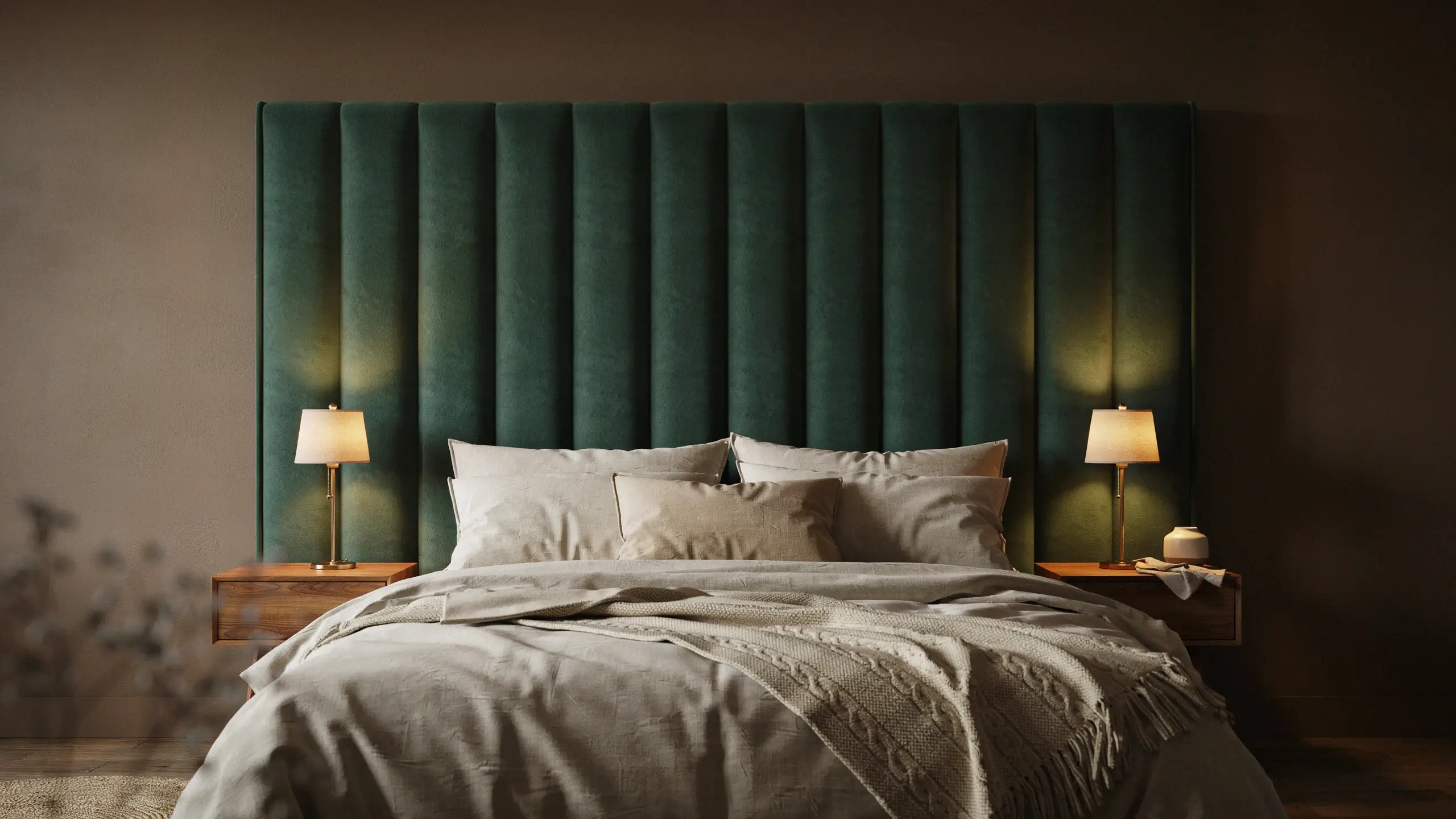Modern bedroom interior featuring a large, jewel-tone emerald green velvet headboard with vertical channel tufting, paired with neutral beige bedding, matching wooden nightstands, and warm ambient light from brass bedside lamps.