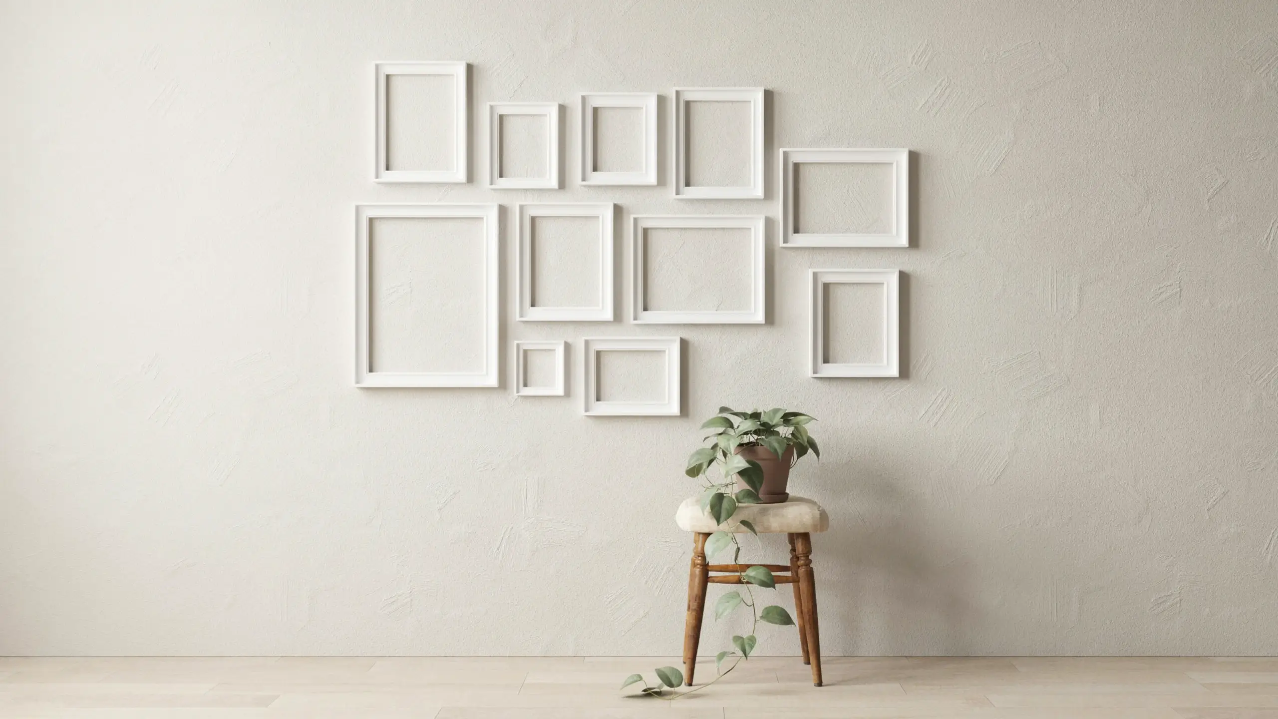 White RIBBA frames arranged as a DIY photo backdrop gallery wall on a textured wall, with a wooden stool, fluffy seat pad, and trailing green plant for a minimalist Scandinavian home decor mockup.