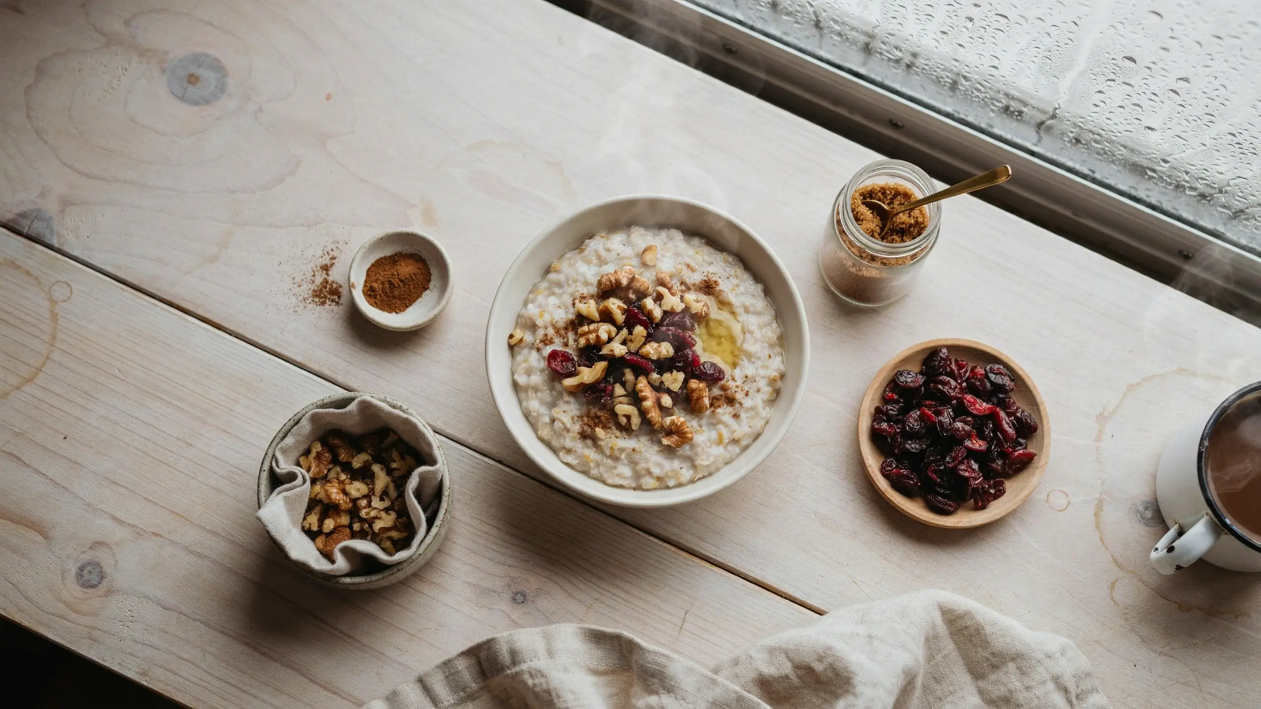 Loaded instant oatmeal bar featuring creamy oats topped with walnuts, dried cranberries, cinnamon, and brown sugar in a white bowl.