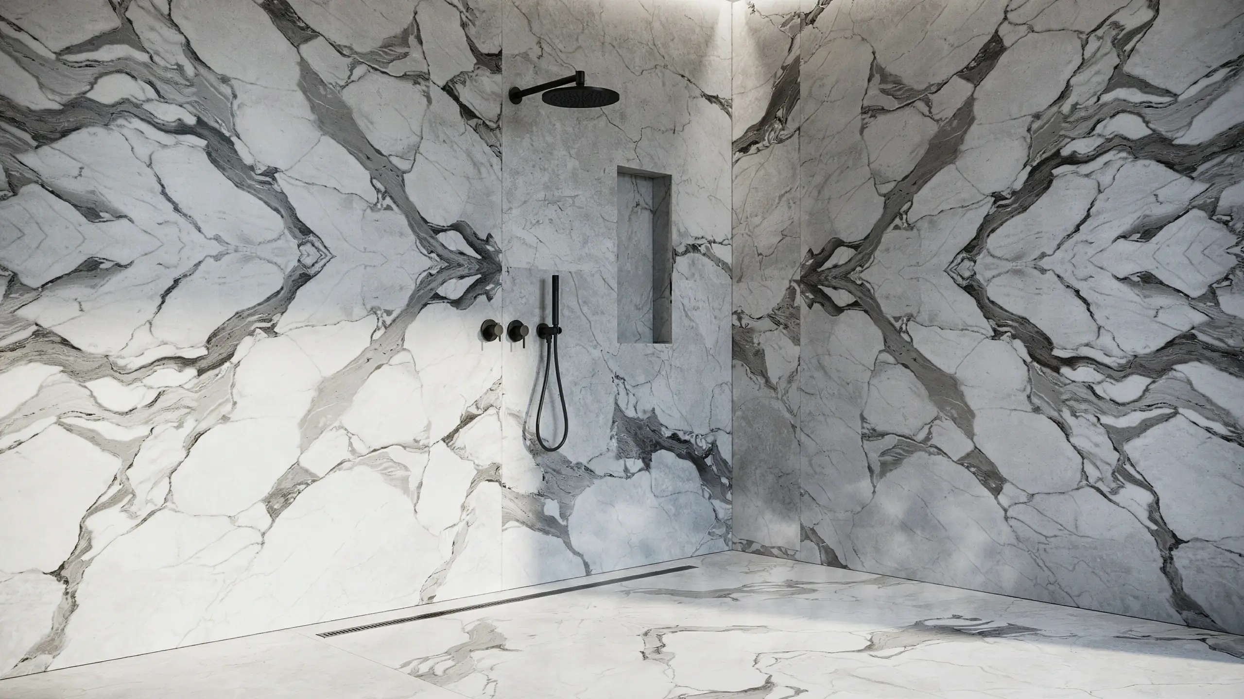 Modern luxury marble walk-in shower featuring matte black rainfall showerhead, handheld wand, control knobs, and a recessed niche, with continuous grey-veined stone flowing seamlessly from the floor to the wall.