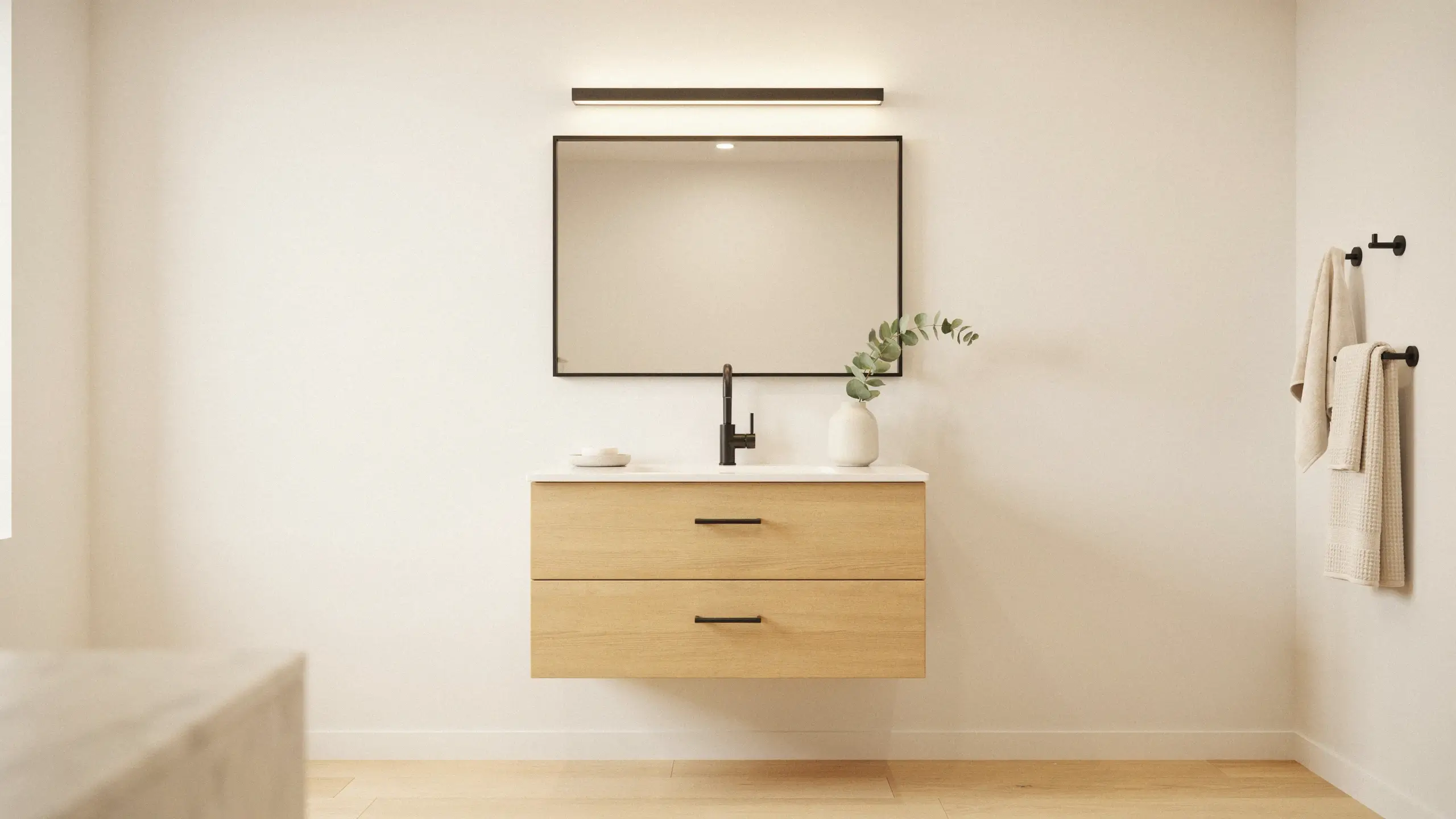 Modern minimalist floating light oak vanity with cohesive matte black drawer pulls, faucet, and mirror frame in a neutral-toned bathroom.