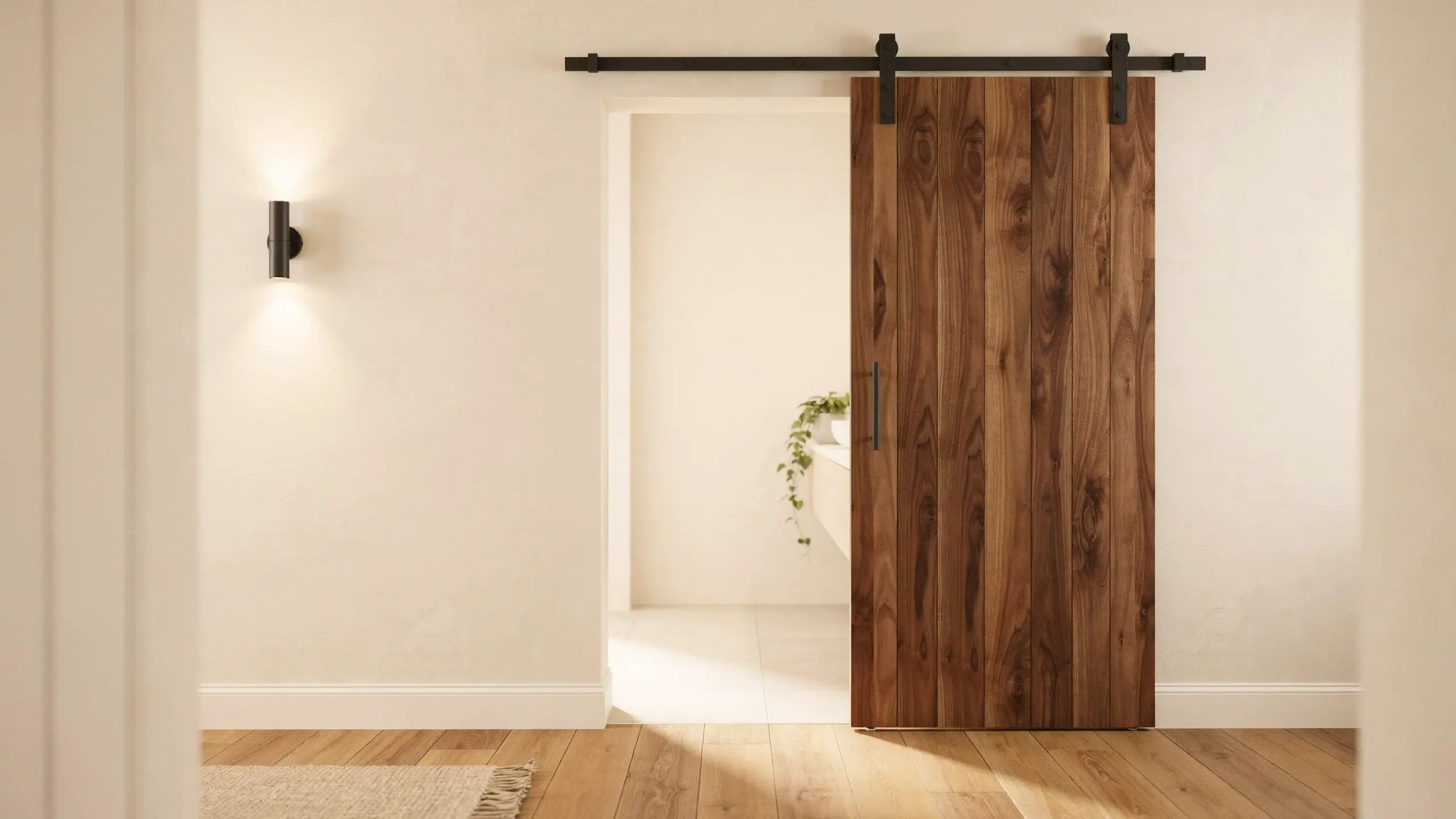 Sliding wooden barn door with black metal track and handle leading to a bright bathroom entryway 