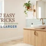 Modern tiny bathroom with light wood vanity, white vessel sink, brass faucet, and sage green subway tile backsplash featuring overlay text about making small spaces feel larger.