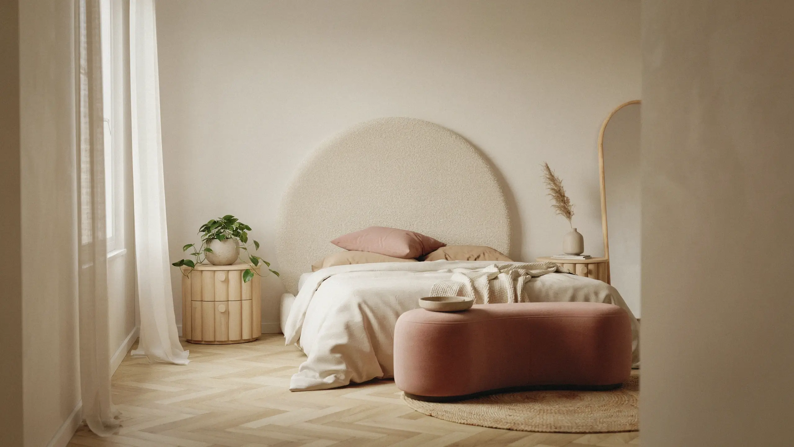 A serene, minimalist bedroom showcasing organic curves and rounded furniture, featuring a large textured boucle headboard, a dusty pink oval ottoman, a circular wooden nightstand, and an arched mirror against a neutral wall.