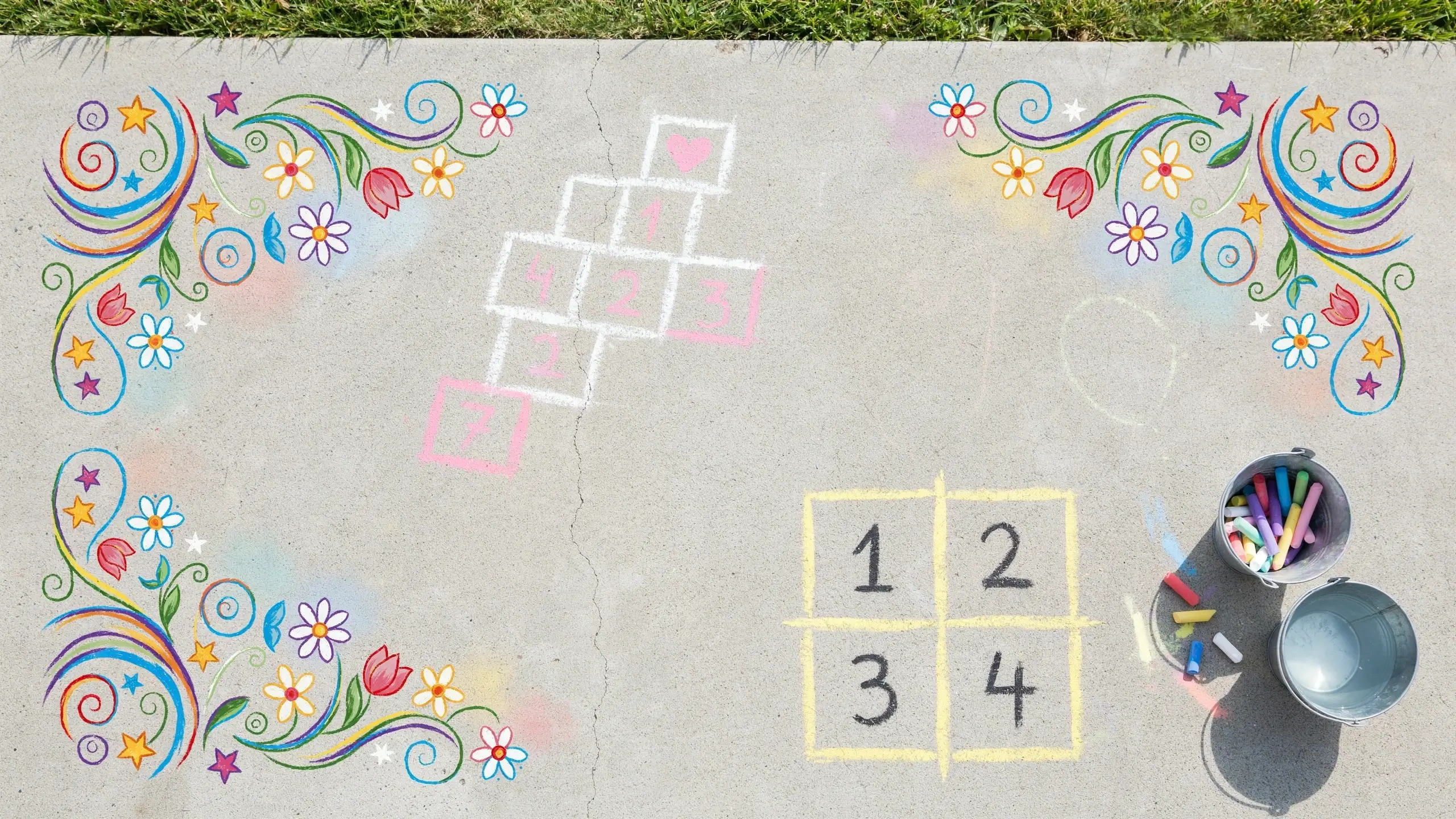 Outdoor concrete patio transformed into a colorful chalk art and game zone with a hopscotch grid, number square, and buckets of sidewalk chalk.