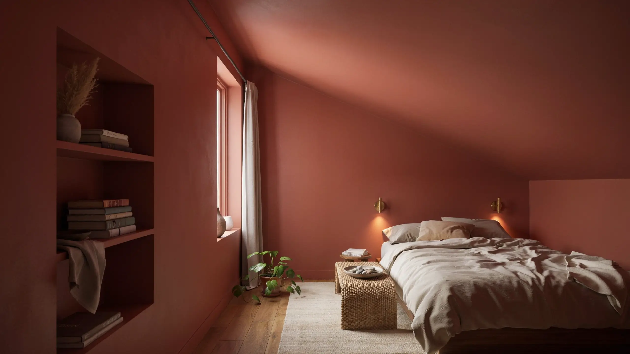 Warm terracotta color-drenched bedroom featuring a sloped attic ceiling, recessed built-in shelves, brass wall sconces, and a bed with neutral cream linens, illuminated by soft natural light.