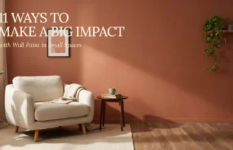 A cream beige armchair with a textured throw blanket sits in a cozy small living room featuring a warm terracotta wall paint. A minimalist wooden side table holds a sage green mug and a stack of books, surrounded by lush indoor trailing plants and warm natural light.