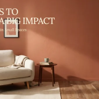 A cream beige armchair with a textured throw blanket sits in a cozy small living room featuring a warm terracotta wall paint. A minimalist wooden side table holds a sage green mug and a stack of books, surrounded by lush indoor trailing plants and warm natural light.