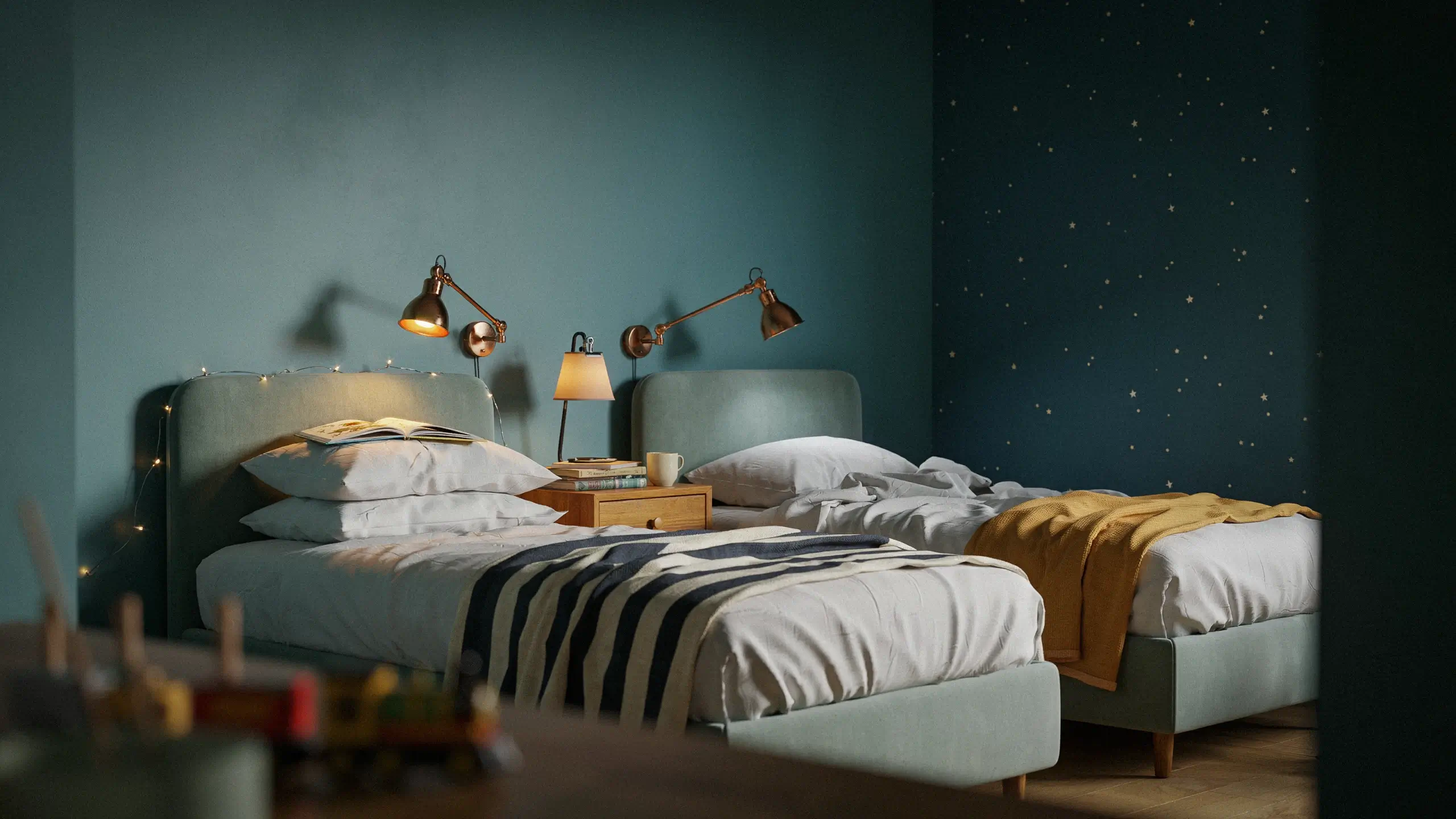 Cozy shared twin bedroom featuring individual brass wall-mounted reading lamps, a central wooden nightstand with an open book and warm mug, and dark navy walls decorated with white star decals.
