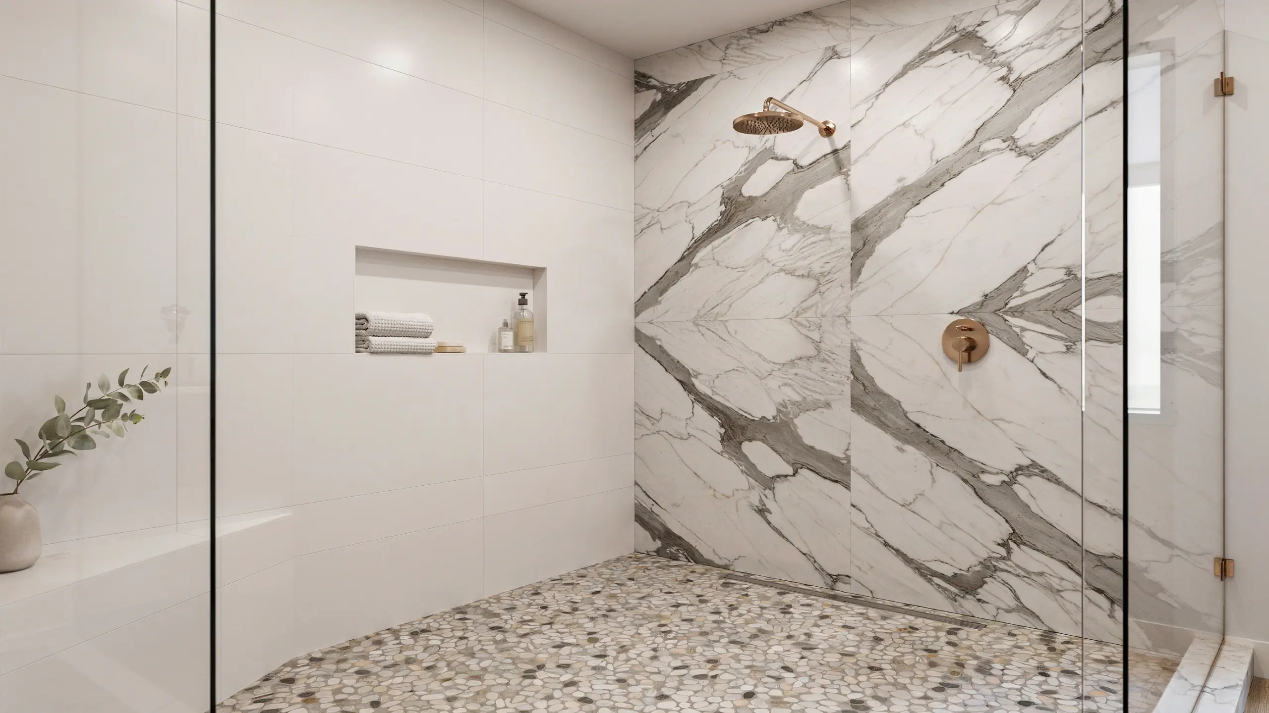 Modern walk-in shower showcasing a two-material tile mix featuring a marble-look feature wall, a natural pebble mosaic floor, and brushed copper fixtures.