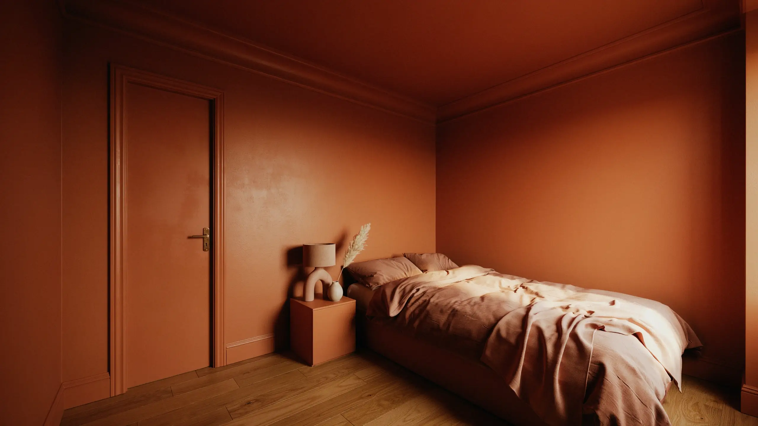 Minimalist monochromatic bedroom painted in warm terracotta rust on the walls, ceiling, door, and nightstand. A bed with rumpled peach linens sits beside a modern beige sculptural tubular lamp and a stem of dried pampas grass, creating a moody boho interior.